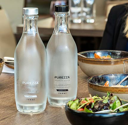 Purezza prémiové láhve stojaté vody podávané v restauraci
